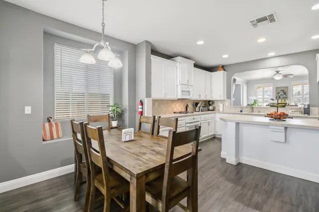 a kitchen with granite countertop a table chairs stainless steel appliances and cabinets