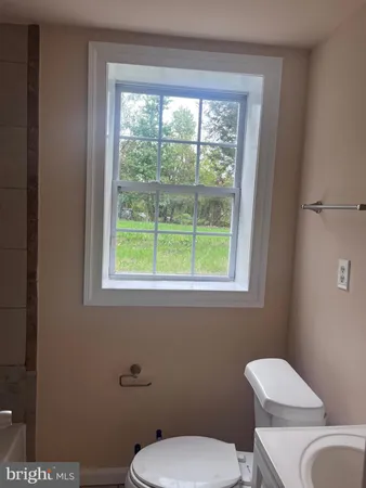 a white toilet sitting next to a window in a bathroom