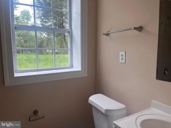 a white toilet sitting next to a window in a bathroom