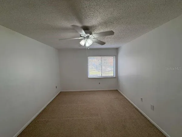 an empty room with windows and ceiling fan