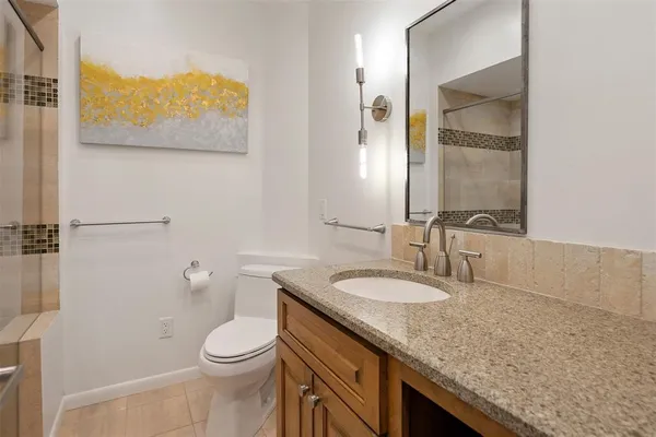 a bathroom with a granite countertop sink a toilet and a mirror