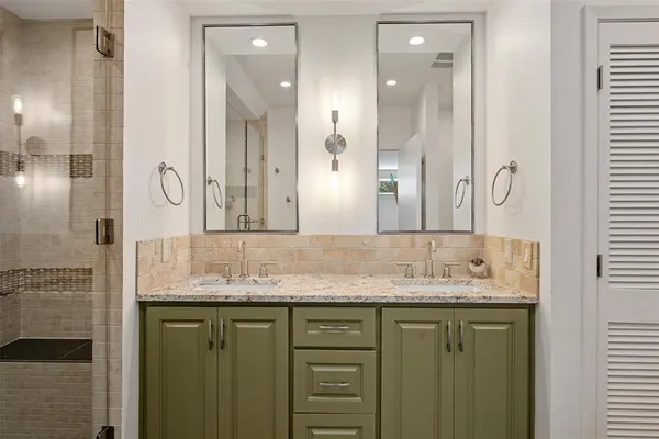 a bathroom with a granite countertop double vanity sink and a mirror