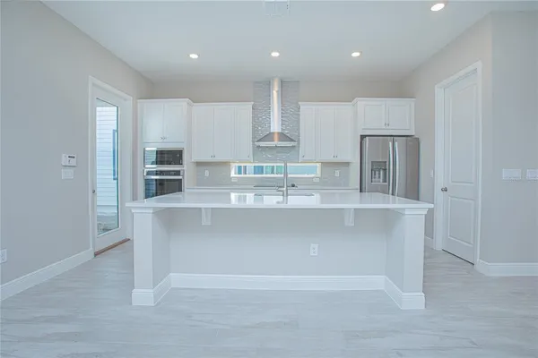 a large kitchen with kitchen island white cabinets and stainless steel appliances