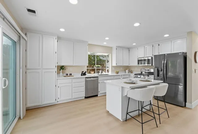 a kitchen with stainless steel appliances kitchen island granite countertop a refrigerator and a stove top oven