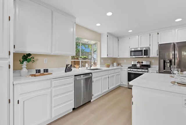 a kitchen with white cabinets sink and stainless steel appliances