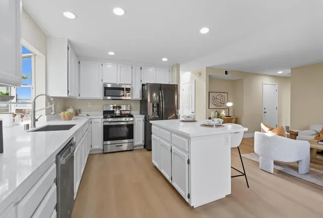a kitchen with kitchen island a white counter top space stainless steel appliances and cabinets