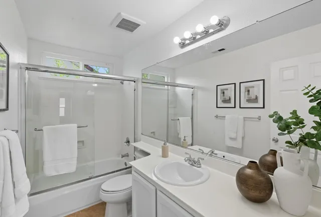 a bathroom with a granite countertop sink a toilet a mirror and shower