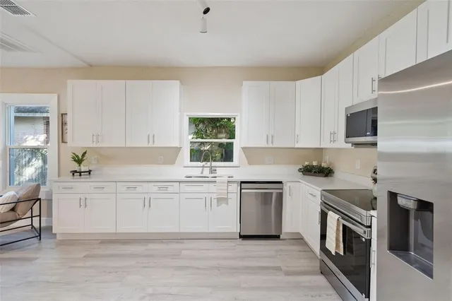 a kitchen with stainless steel appliances granite countertop a stove top oven a sink dishwasher and a refrigerator