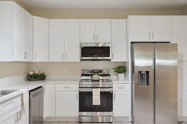 a kitchen with white cabinets and stainless steel appliances