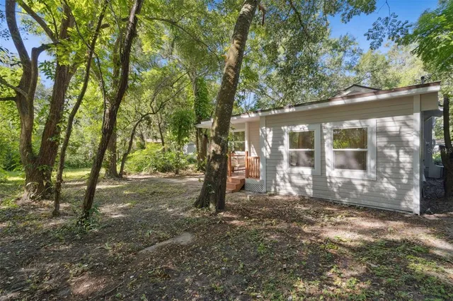 a view of a house with backyard and trees