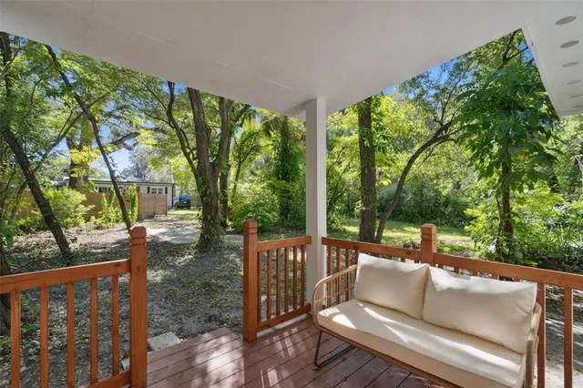 a view of a patio with couches plants and large trees