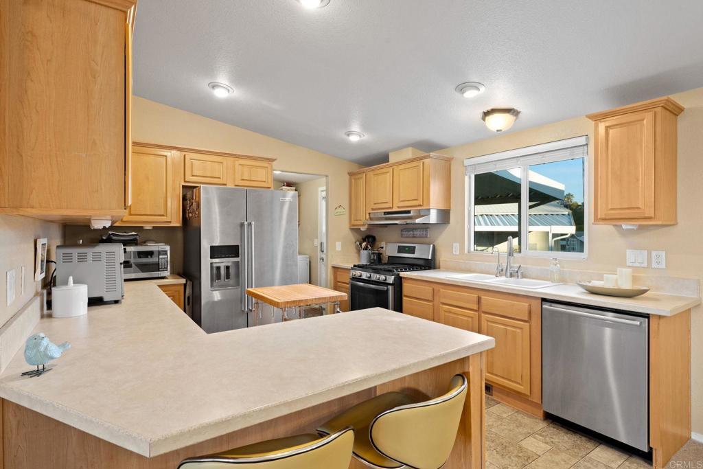 9100 Single Oak Drive, Unit 26 Lakeside, CA 92040 - Photo 4 of 46 a kitchen with a refrigerator a stove a sink a oven with wooden floor and cabinets
