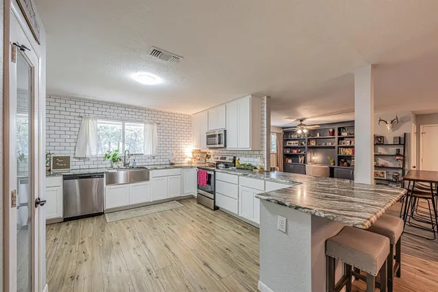 a kitchen with stainless steel appliances kitchen island granite countertop a stove refrigerator and cabinets