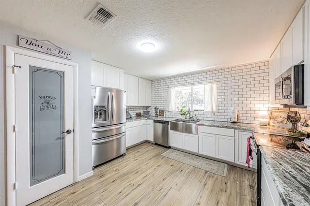a kitchen with white cabinets and stainless steel appliances
