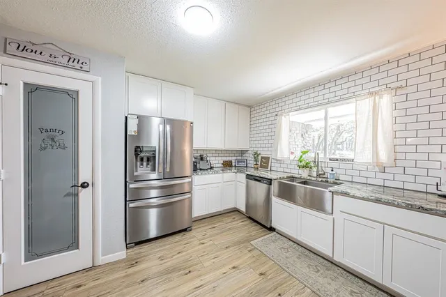 a kitchen with a sink a refrigerator and wooden floor