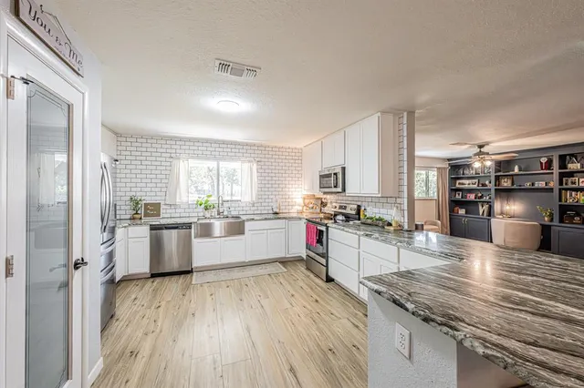 a kitchen with a center island wooden floor and stainless steel appliances