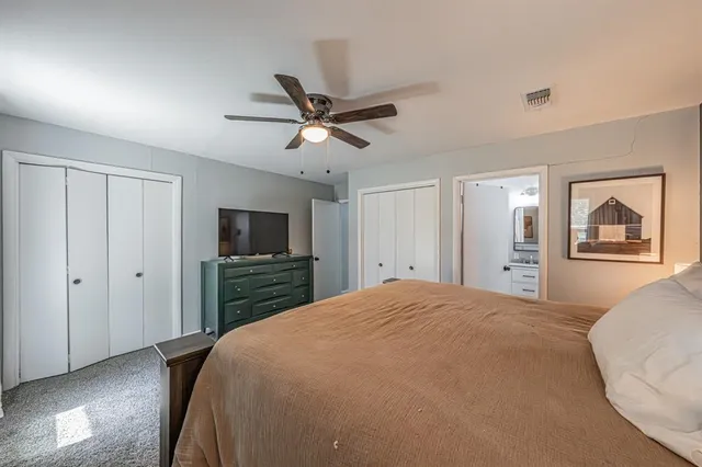 a bedroom with a large bed a flat tv screen and dresser