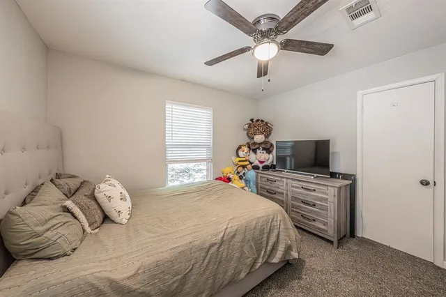 a bedroom with a bed and a flat tv screen on the dresser