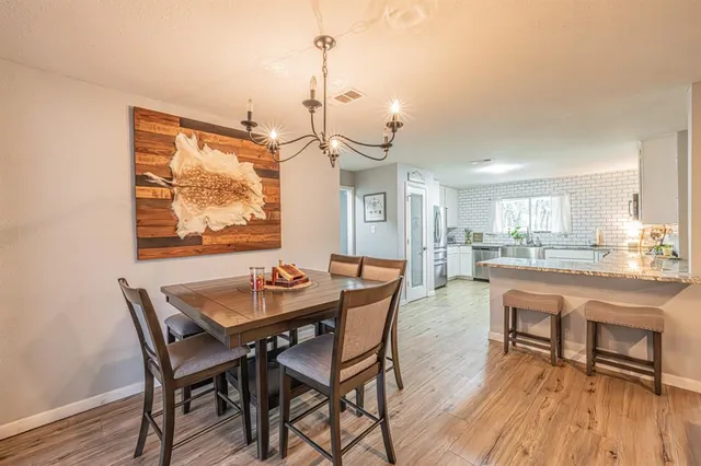 a dining room with wooden floor a chandelier a wooden table and chairs