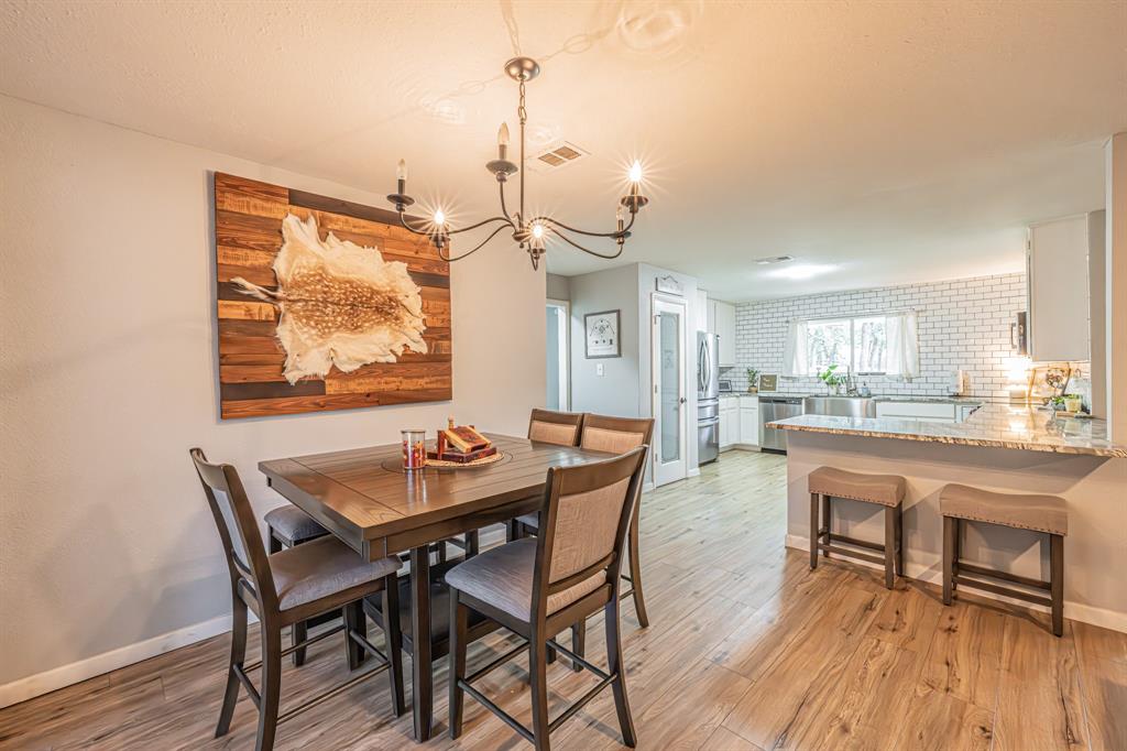 3745 Lucy Trimble Road Burleson, TX 76028 - Photo 9 of 40 a dining room with wooden floor a chandelier a wooden table and chairs