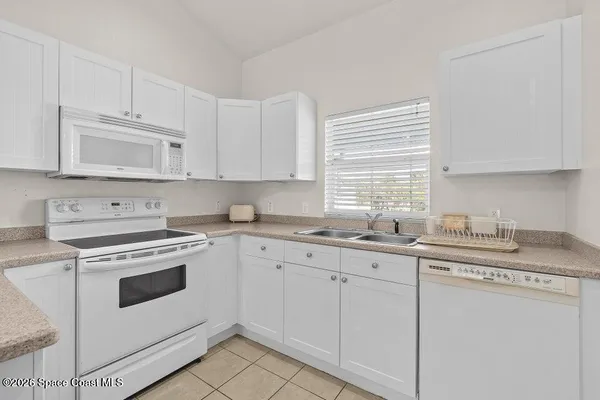 a kitchen with granite countertop white cabinets and white appliances