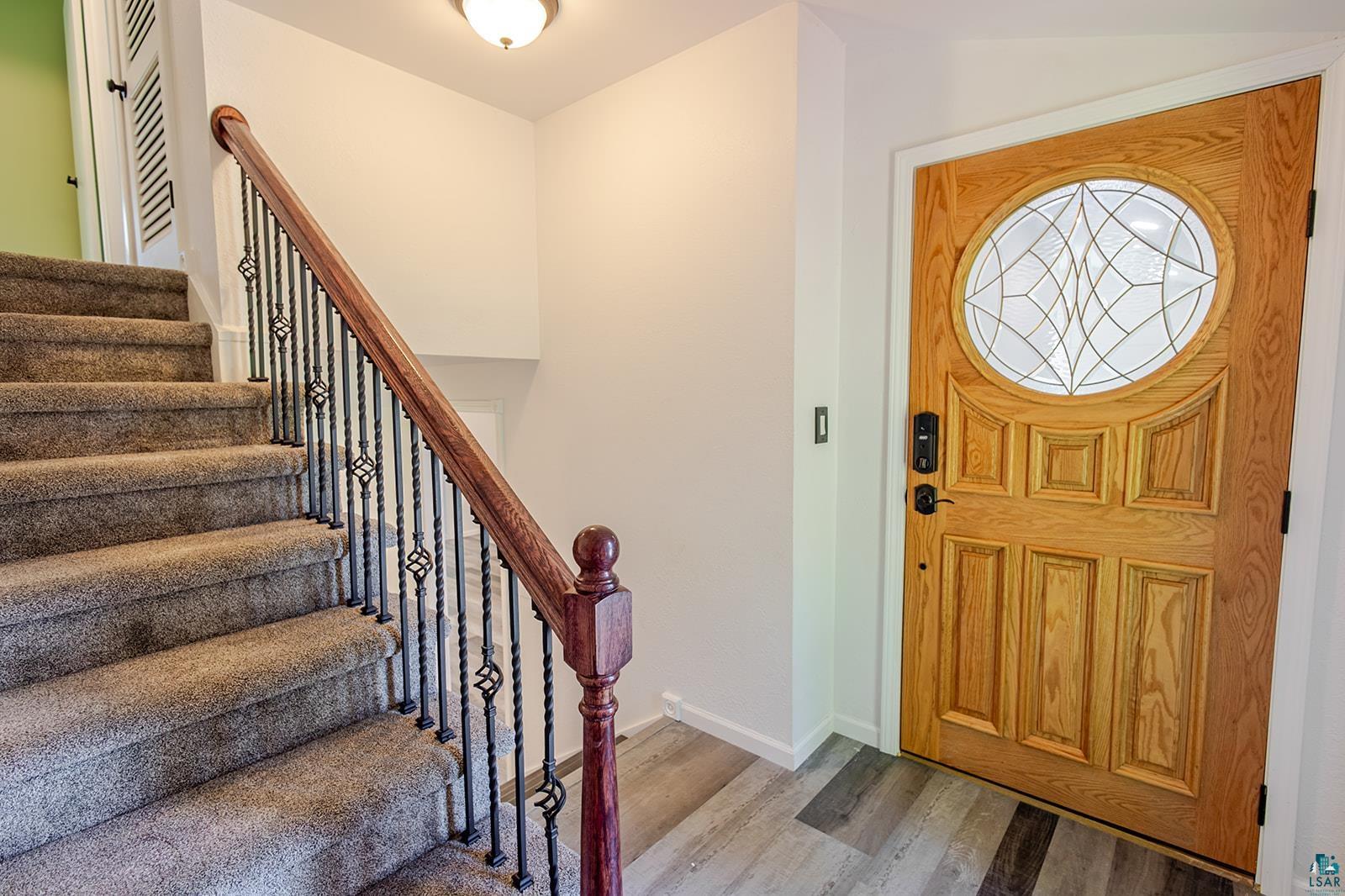 29 Ridge Road Esko, MN 55733 - Photo 8 of 41 Entryway featuring a paneled wood door with a circular decorative glass insert, complemented by multi-tone wood-finish flooring
