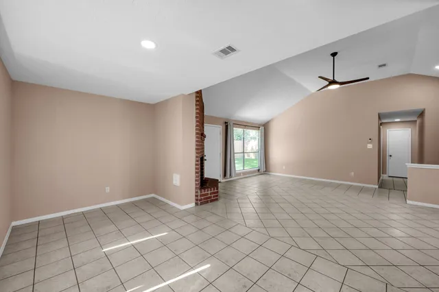 a view of an empty room with window and chandelier fan
