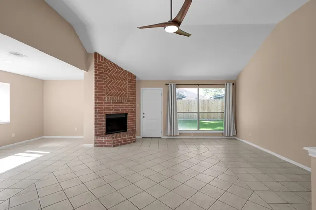 a view of an empty room with a fireplace and a window