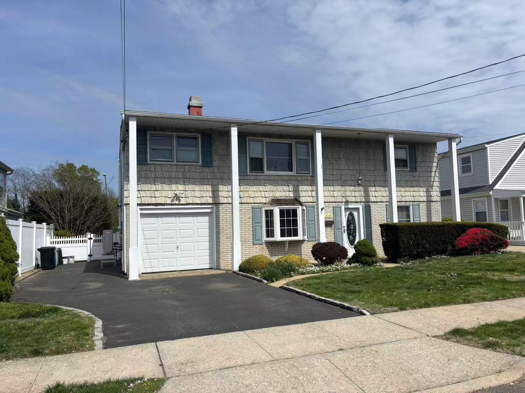 View of front of home featuring a chimney, driveway, a garage, and brick siding
