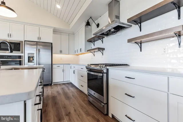 a kitchen with stainless steel appliances white cabinets and wooden floors