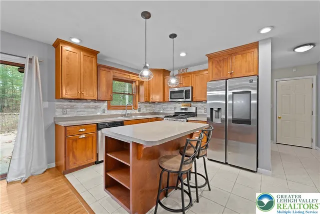 a kitchen with stainless steel appliances a stove a refrigerator a sink a oven with a dining table and chairs