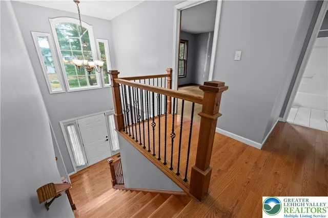 a view of a hallway to a window with wooden floor
