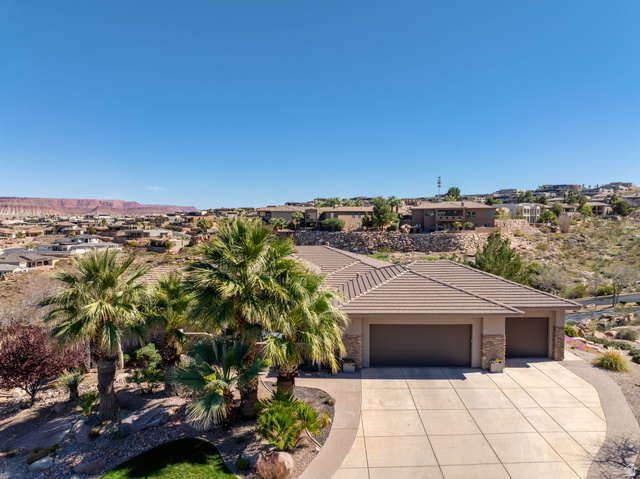 View of front facade featuring an attached garage, stone siding, a residential view, and stucco siding