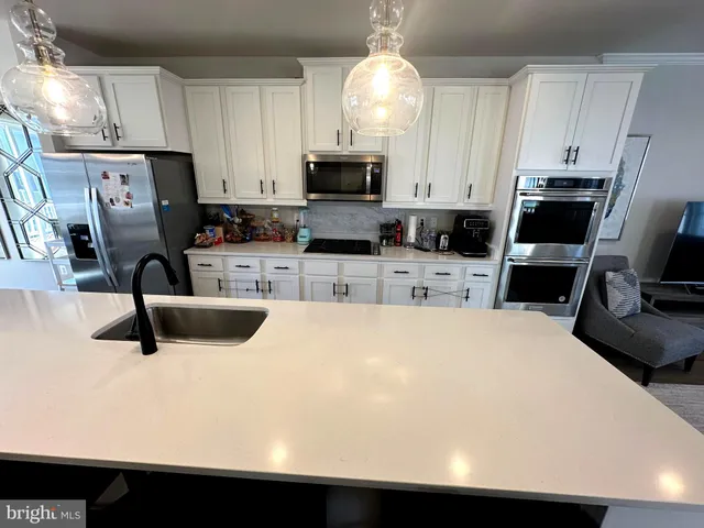 a kitchen with stainless steel appliances a stove refrigerator a sink a stove and microwave