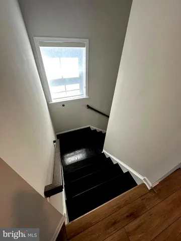a view of an empty room with wooden floor and stairs