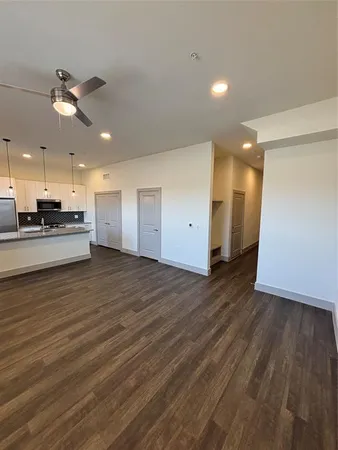 a view of kitchen and empty room with wooden floor