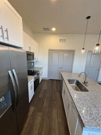 a kitchen with granite countertop a refrigerator a stove a sink and dishwasher with wooden floor