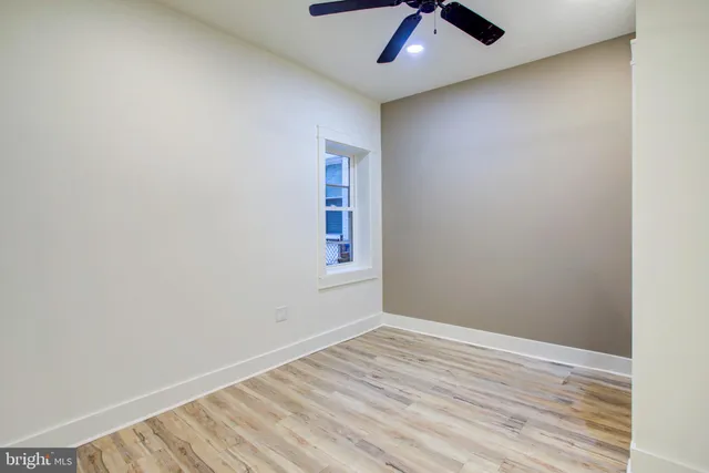 an empty room with ceiling fan and window