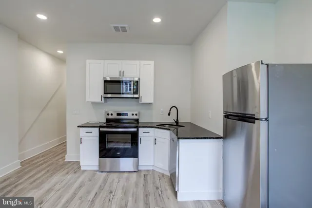 a kitchen with granite countertop a refrigerator stove and sink