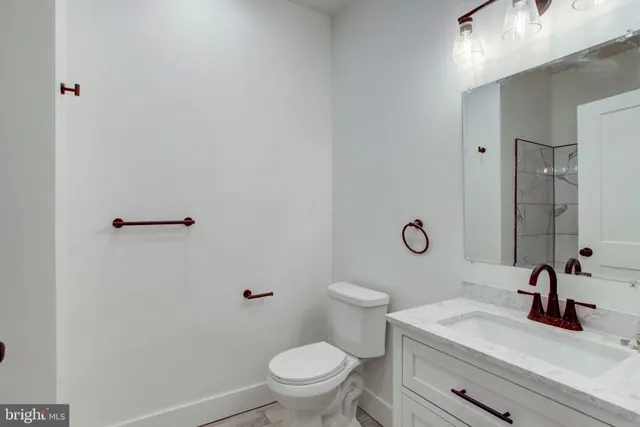 a bathroom with a sink a toilet a mirror and shower