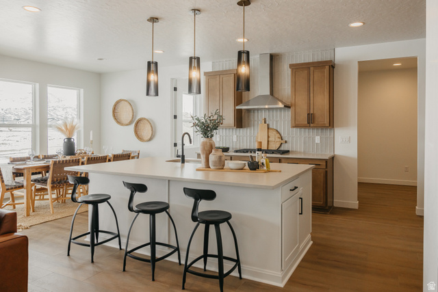 1066n South State Road, Unit ATWOOD Salem, UT 84653 - Photo 15 of 29 Kitchen island with an undermount sink and matte black faucet, wood-finish flooring, and light wood cabinetry with a tile backsplash