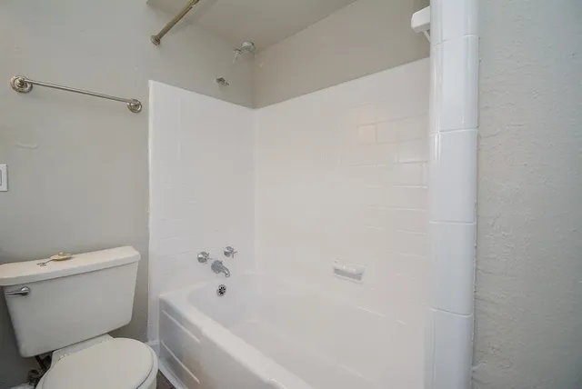 a white toilet sitting next to a bath tub