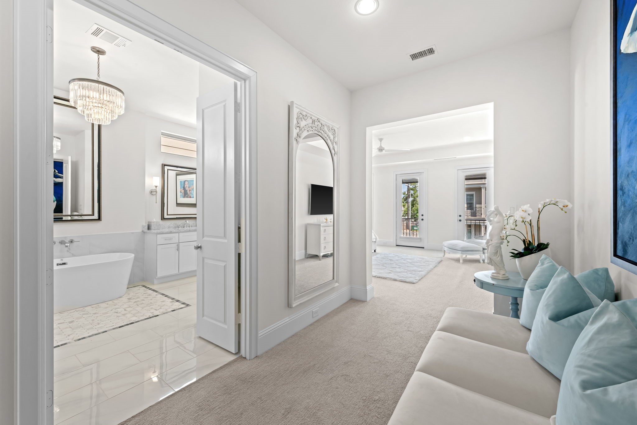 110 East 26th Street, Unit B Houston, TX 77008 - Photo 23 of 43 This alternate perspective highlights the exclusive entry space and versatile sitting room tucked behind the primary suite’s double doors. The layout showcases the impressive scale of this secluded wing, offering a sneak peek of the luxurious bathroom suite beyond. The seamless flow between these areas emphasizes the high-end, cohesive design, reinforcing a true resort-style experience that remains completely separate from the rest of the home.