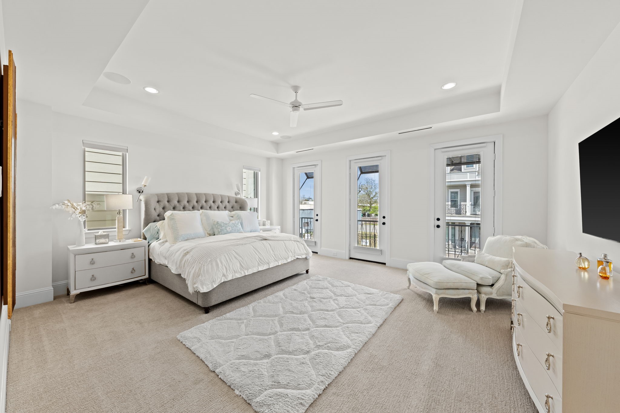 110 East 26th Street, Unit B Houston, TX 77008 - Photo 24 of 43 This expansive bedroom is the definition of luxury, featuring a refined tray ceiling and a wealth of natural light from five large windows. Three Juliet balconies offer a sophisticated architectural touch and fresh air, while high-end plush carpet underfoot ensures the space feels like a true private haven.
