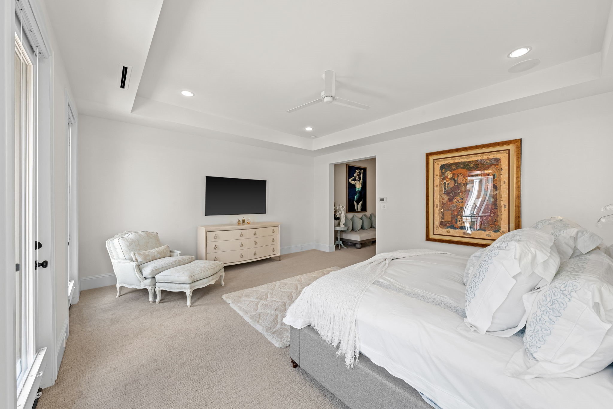 110 East 26th Street, Unit B Houston, TX 77008 - Photo 25 of 43 This alternate view highlights the impressive volume of the room, where high ceilings flow effortlessly from the sleeping quarters into the private sitting area. The open, airy design provides a seamless transition toward the luxurious primary bath, emphasizing the suite's grand scale and cohesive layout.