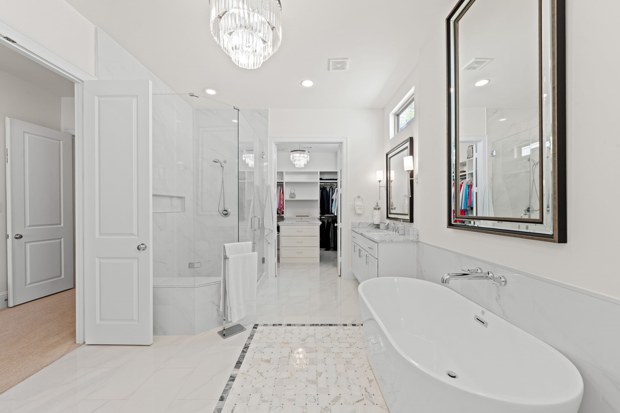 110 East 26th Street, Unit B Houston, TX 77008 - Photo 28 of 43 This view from the primary bath leads into a massive walk-in closet, a masterclass in well-thought-out design. The space features a custom center island for additional storage and organization, offering ample room for a complete wardrobe. It is an expansive, boutique-style closet that balances functionality with high-end luxury—closer view of the custom details are available upon request.