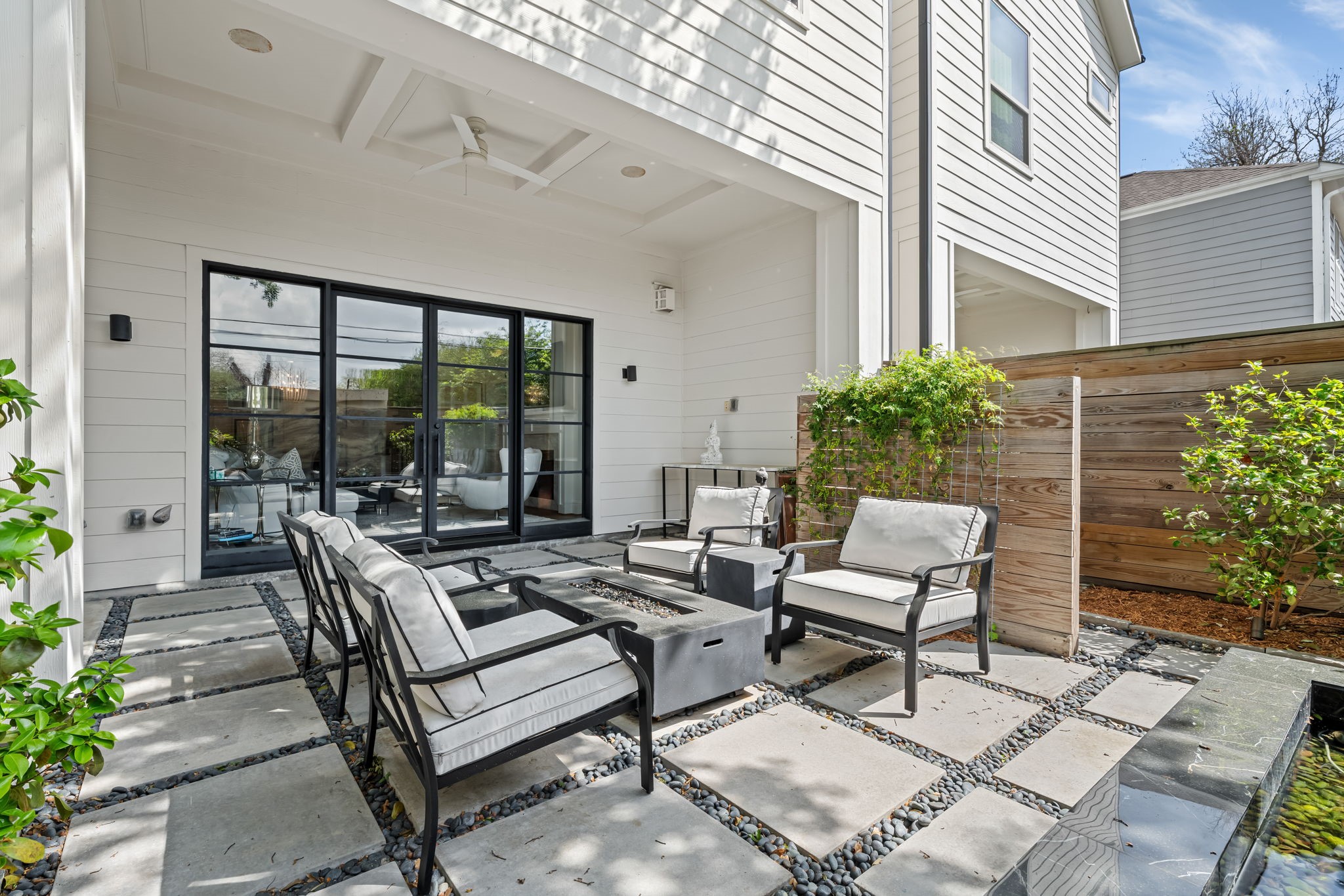 110 East 26th Street, Unit B Houston, TX 77008 - Photo 36 of 43 The backyard oasis also features an elegant covered patio, complete with a tray ceiling and a cooling fan for year-round comfort. Enhancing the space are the marble table and firepit, which convey with the property, making it ready for immediate enjoyment. Surrounded by lush greenery and thoughtfully designed low-maintenance landscaping, this yard is perfectly tailored for a lock-and-leave lifestyle without sacrificing beauty or tranquility.