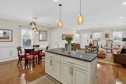 a view of a dining room and livingroom with furniture wooden floor a rug a flat screen tv a rug a fireplace and a chandelier