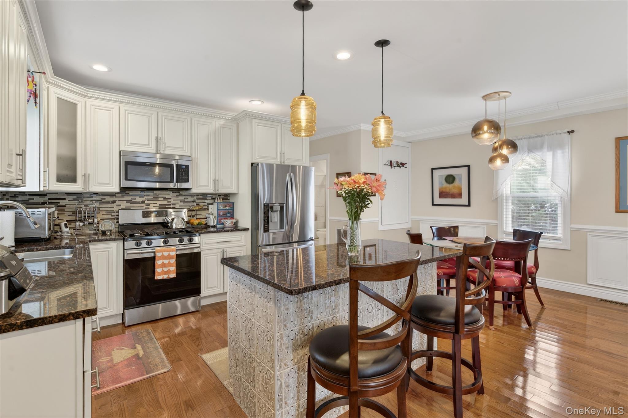 35 Kent Street Beacon, NY 12508 - Photo 15 of 42 a kitchen with stainless steel appliances granite countertop a stove top oven a refrigerator a sink dishwasher a dining table and chairs with wooden floor