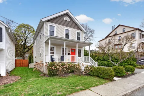 a front view of a house with a yard and potted plants
